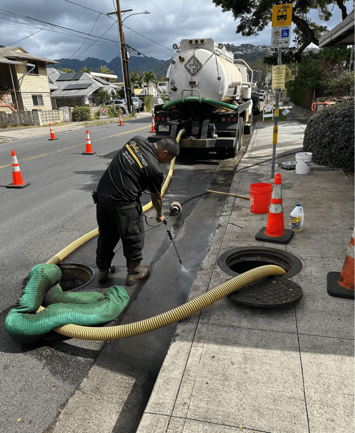 Alpha Omega Plumbing pump truck servicing a residential septic tank on a Honolulu street — Alpha Omega Plumbing